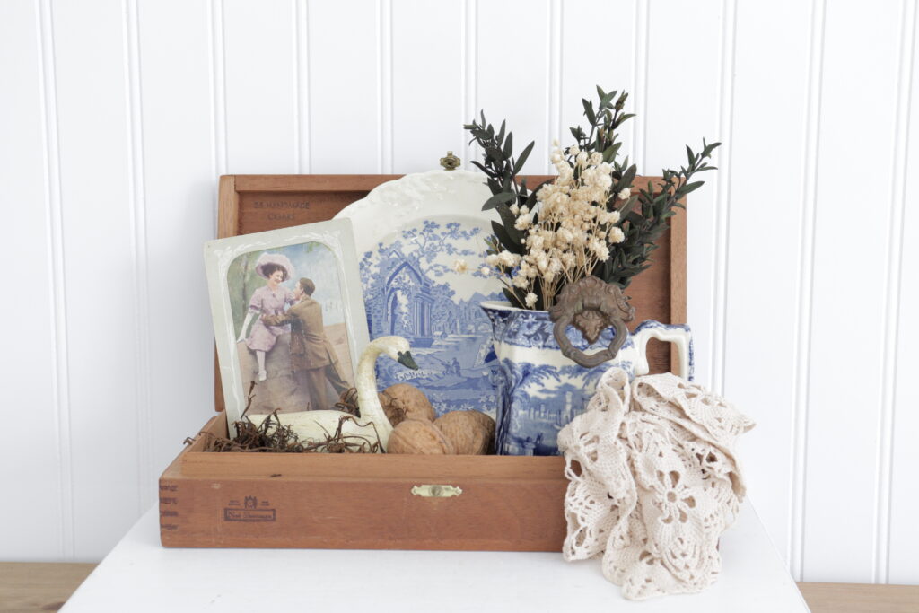 Vintage items including cigar box, ironstone dish ware, floral bouquet, doily, and antique postcard